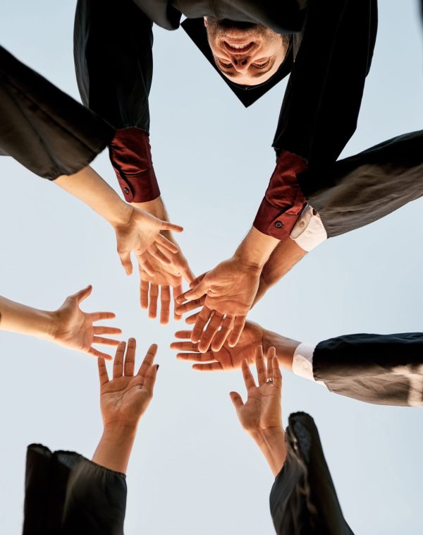 closeup-shot-of-a-group-of-students-joining-their-2022-10-05-00-19-03-utc Closeup shot of a group of students joining their hands together in celebration on graduation day.