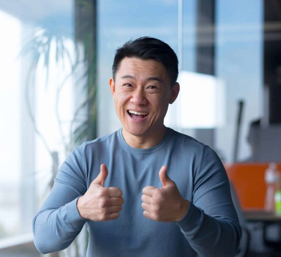 Portrait of a cheerful employee, looking at the camera and gesturing with his hands, Asian communicates on a video call, looks at the webcam